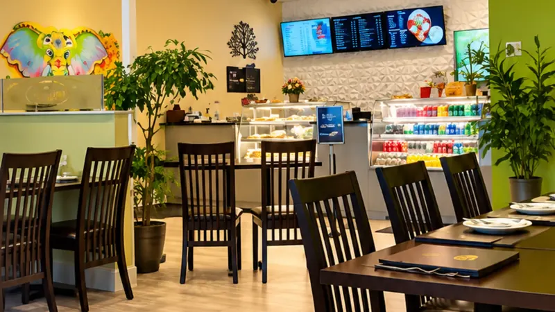 Dining room at The Bombay Grill Milton with dark wood tables, menu screens and the front counter